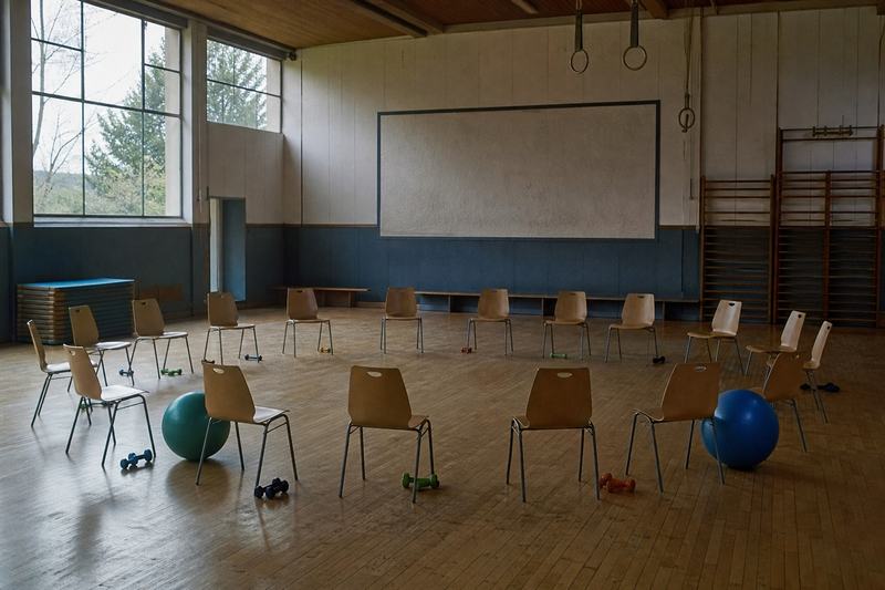 Turnhalle mit einem Stuhlkreis, Handgewichten und zwei Gymnastikbällen