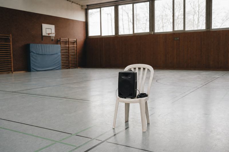 Kleiner tragbarer Lautsprecher auf einem Stuhl in einer leeren Turnhalle