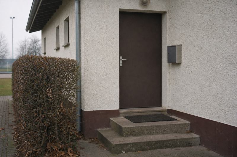 Eingang eines einfachen Vereinsheims mit Tür, Briefkasten und zwei Stufen